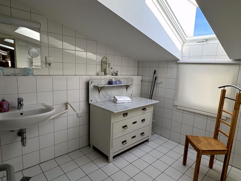 Modernes Duschbad mit Wickelkommode und Tageslicht.
